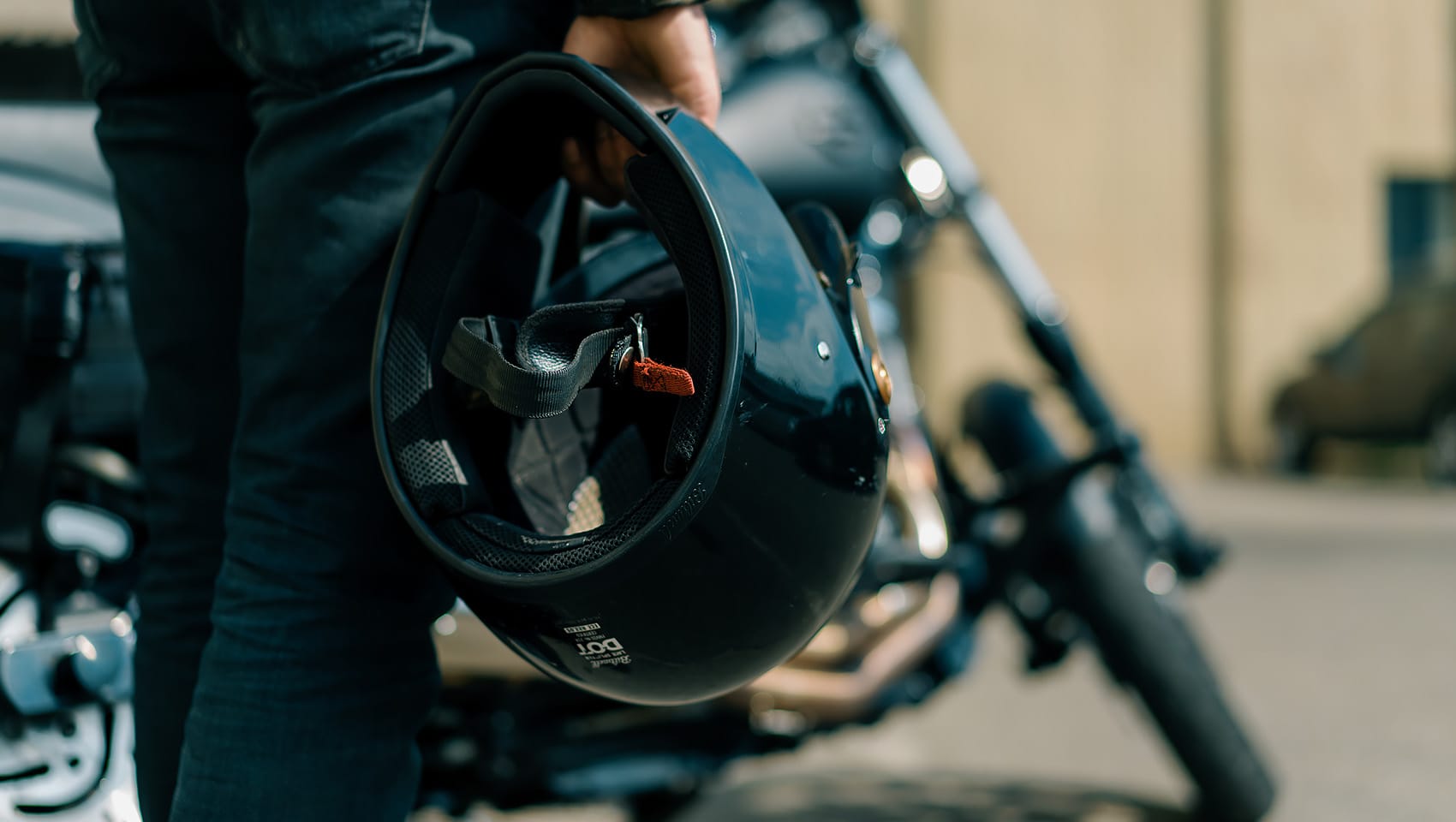 Man walking on the street with a helmet towards his motorcycle