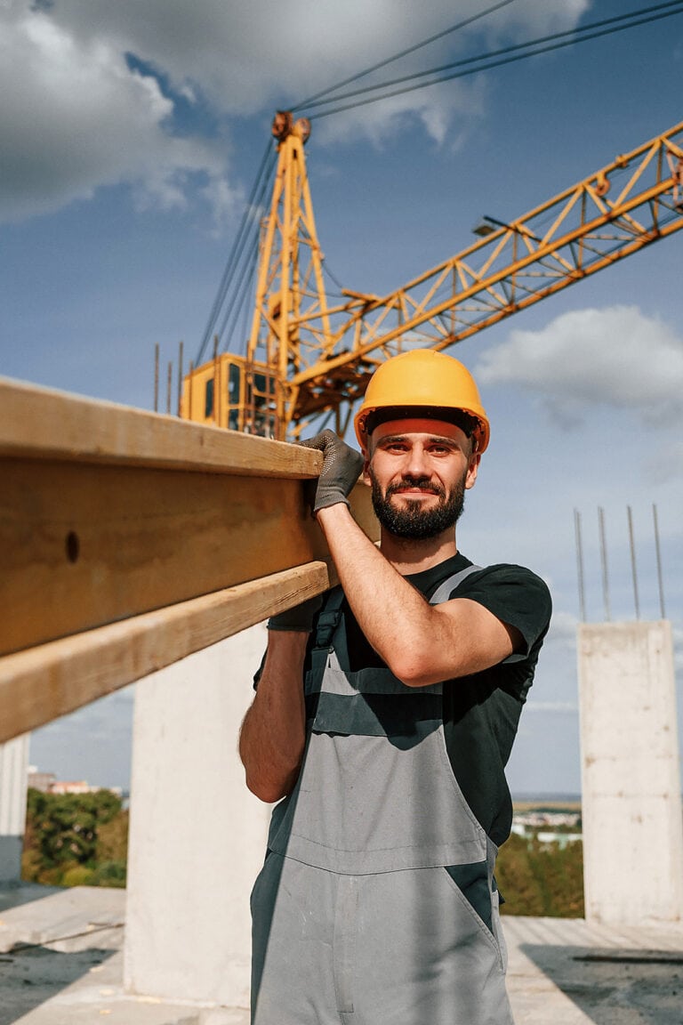 Man with a wood beam at a construction site